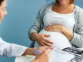 Lekarz konsultuje pacjentkę w 36 tygodniu ciąży. Na stole leżą zdjęcia USG.