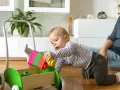 8 miesięczne dziecko raczkuje i bawi się kolorowymi klockami w wózku-pchaczu.