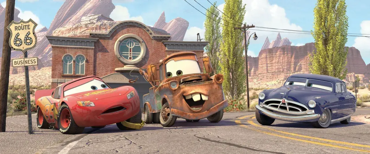 Zabawne auta z bajki: Zygzak McQueen, Złomek i Doc Hudson na tle Route 66.