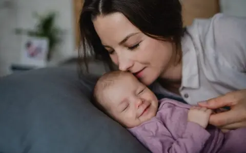 Mama całuje śpiące dziecko. Wkrótce wybierzemy dla niej słodkie imiona dla dziewczynki.