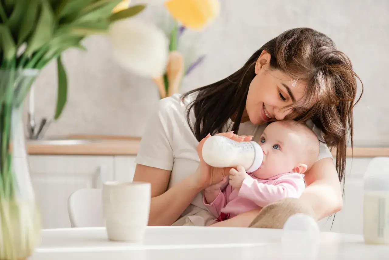 Mama karmi butelką dziecko, szukając odpowiedzi na pytanie: jakie mleko dla noworodka?