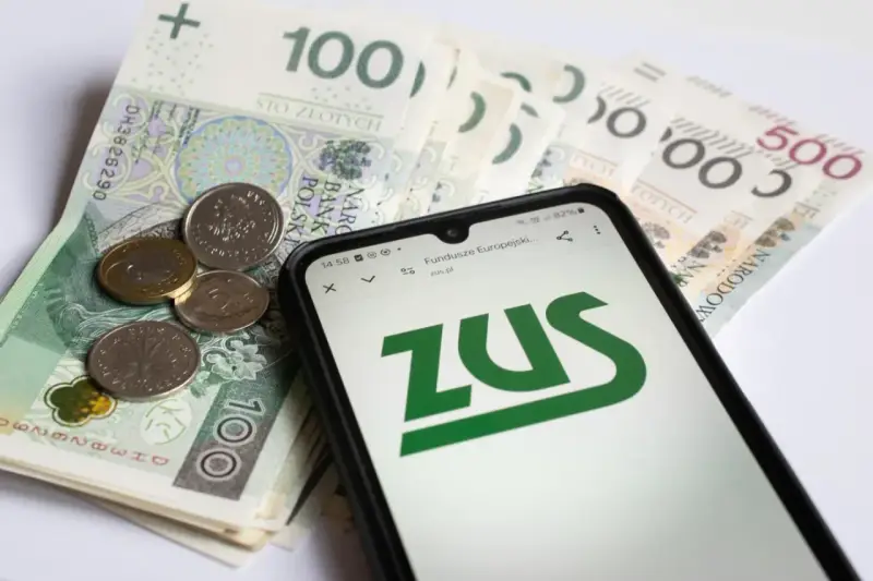 Złotówki i monety obok telefonu z logo ZUS. Może to być związane z wnioskiem o zasiłek opiekuńczy.